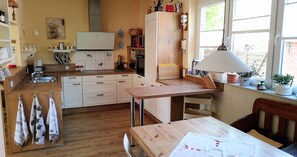 A kitchen with white cabinets, a wooden countertop, a dining table, and a window with a view. - Toennihuus: A Large, Family-Friendly Vacation Home—Accommodates Up to 10 People (Tönning)