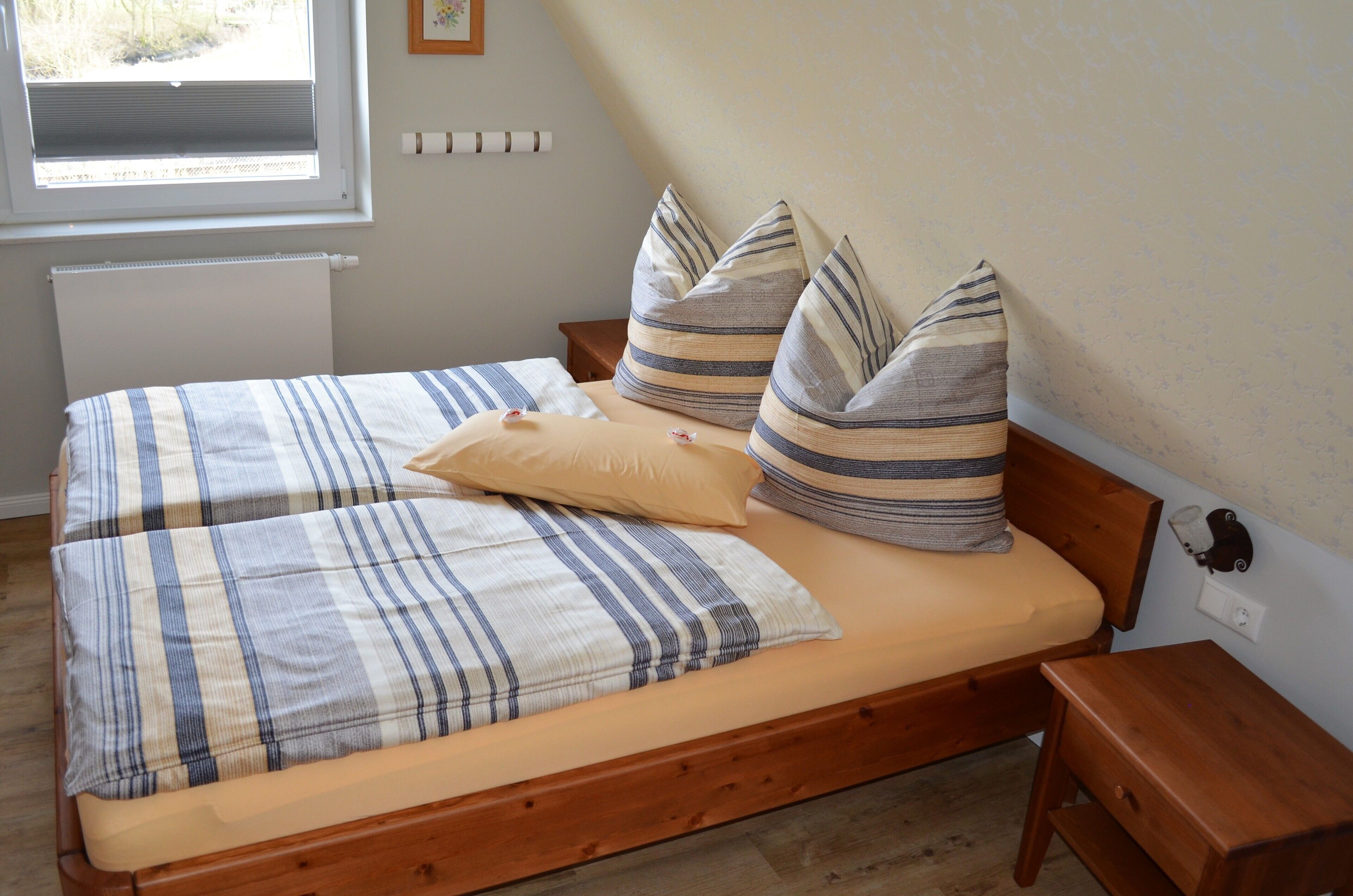 Ein Bett mit gestreifter Bettwäsche, einem Holz-Kopfschild und einem Nachttisch.