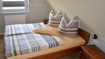 Ein Bett mit gestreifter Bettwäsche, einem Holz-Kopfschild und einem Nachttisch.