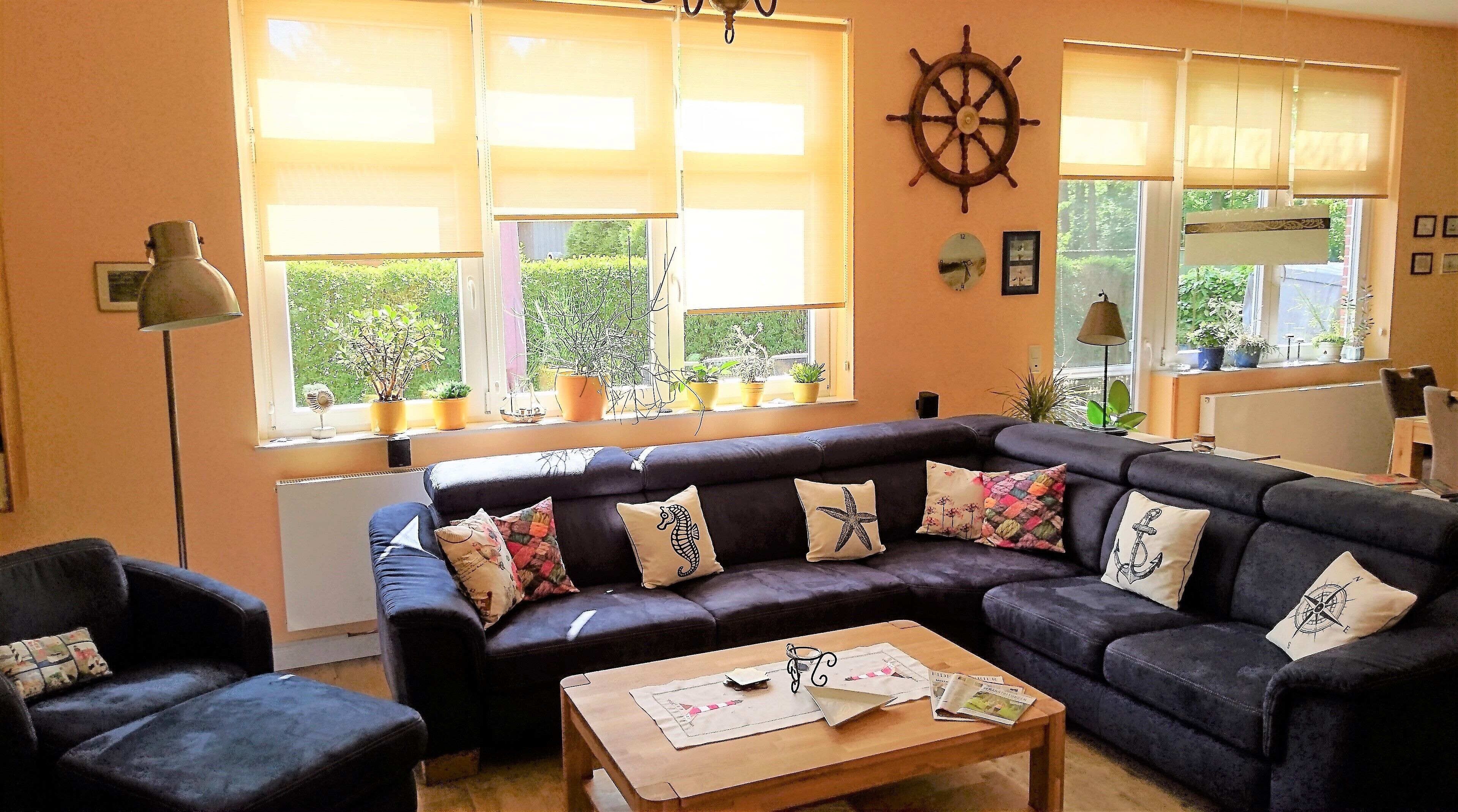 Ein Wohnzimmer mit einem dunkelbraunen Ledersofa, einem Couchtisch mit Zeitschriften und einer Schiffslenken-Dekoration an der Wand.
