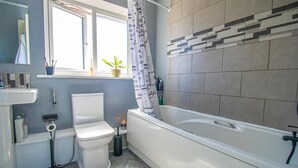 Un bagno con il water, un lavandino, una vasca e una finestra con tenda.