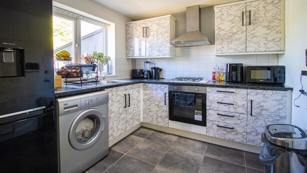 Una cucina moderna dotata di lavatrice, forno, microonde e dispenser di acqua.