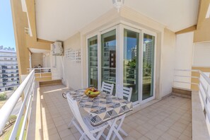 Ein Balkon mit Tisch, Stühlen und einer Obstschale.
