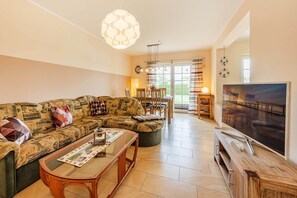 Ein Wohnzimmer mit Sofa, Couchtisch, Fernseher und Essbereich.