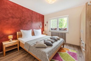 Ein Schlafzimmer mit Bett, Nachttischen, einem Fenster und einem Kleiderschrank.