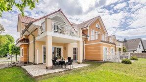 A two-story house with a balcony, a patio with outdoor furniture, and a well-maintained lawn. - Family-friendly vacation rental with a terrace and Wi-Fi—close to the beach in a quiet location (Koserow)