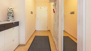 A narrow hallway with a white door, a black rug, and a white cabinet with drawers. - Family-friendly vacation rental with a terrace and Wi-Fi—close to the beach in a quiet location (Koserow)