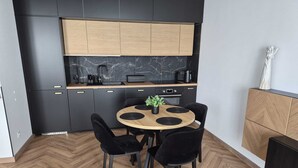 Una cocina moderna con armarios negros, encimera de madera y una mesa de comedor redonda con sillas negras.