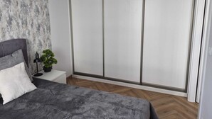 Un dormitorio con cama, mesita de noche, planta en maceta y puerta corredera al armario.