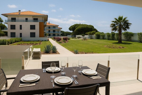 A dining area with a table set for four, outdoor seating, and a view of a modern building and landscaped garden.