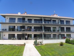 A modern multi-story building with balconies, large windows, and a clear sky.