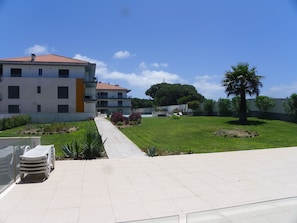 A courtyard with a pool, lounge chairs, and a building with balconies.