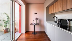Eine moderne Küche mit einem Holzkasten, einer schwarzen Kaffeemaschine und einem kleinen Tisch mit einer Vase und einem Glas.