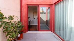 Eine rote Außenwand, eine Schiebetür aus Glas, ein Blumentopf und ein Blick in den Innenraum.