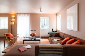 Ein modernes Wohnzimmer mit einer Couch, einem Sessel, einem Couchtisch und einer Lampe.