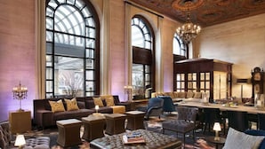 A spacious lounge with a large arched window, leather furniture, and a chandelier.