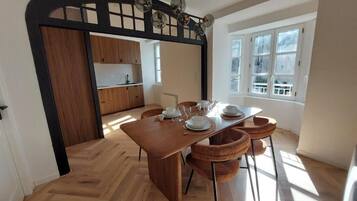 Un espace repas avec une table en bois, des chaises et une cuisine en arrière-plan.
