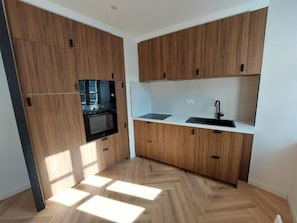 A compact kitchen with wooden cabinets, a built-in microwave, and a sink.