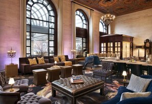Tilava oleskelutila, jossa on suuri kaareva ikkuna, nahkaverhoiltuja huonekaluja ja koristeellinen kattokruunu.