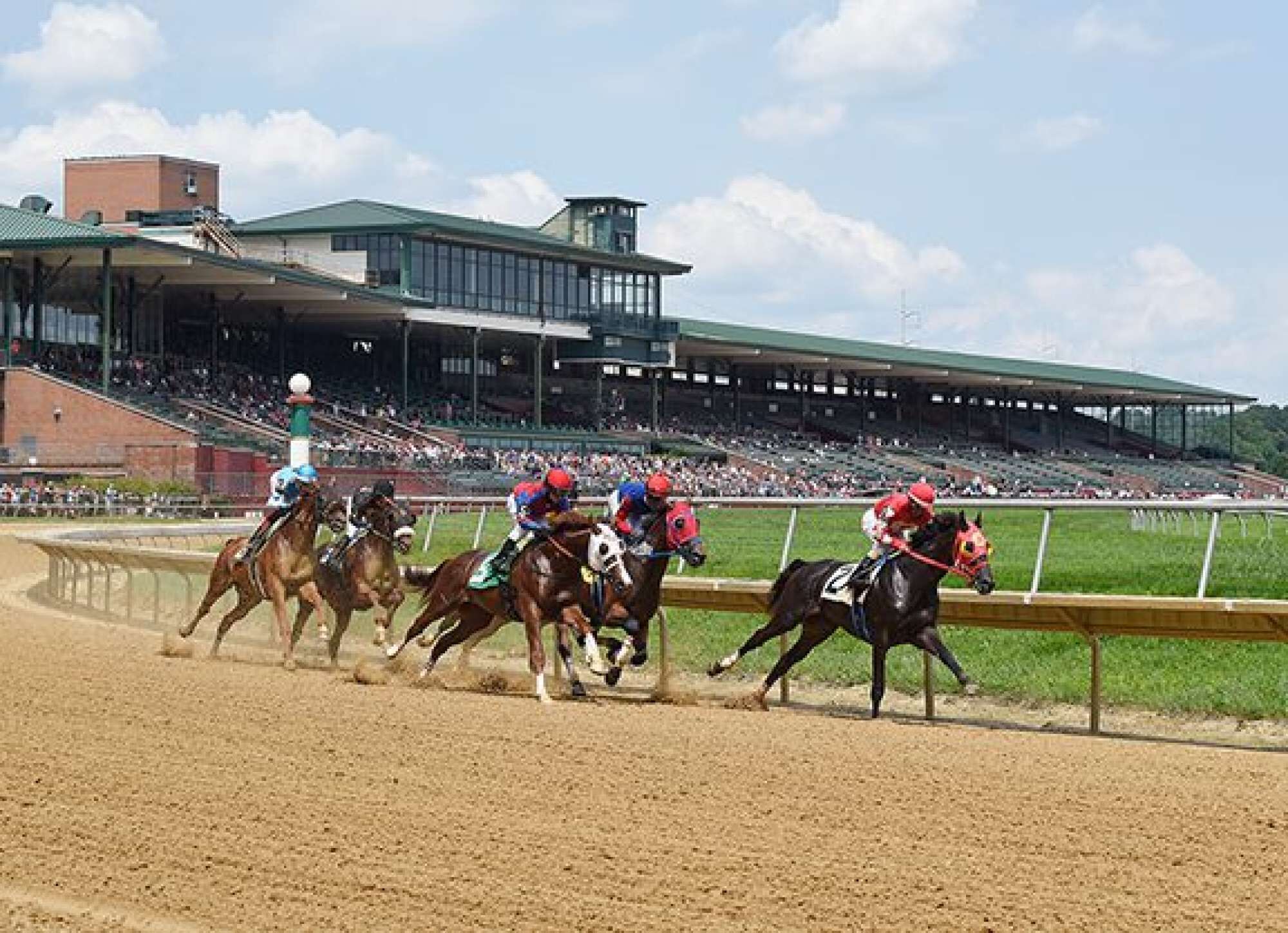 A horse race track with a grandstand and a large building in the background.