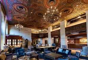 Een statige lobby met gedetailleerde plafonddecoraties, een kroonluchter en een bar.