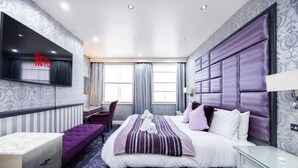 Une chambre d’hôtel moderne équipée d’un grand lit, d’un bureau, d’une chaise, d’une télévision et d’une armoire.