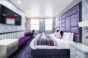 Une chambre d’hôtel moderne équipée d’un grand lit, d’un bureau, d’une chaise, d’une télévision et d’une armoire.