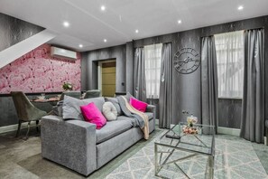 A modern living room with a grey sofa, a glass coffee table, and a wall clock. - Comfy & Spacious Marylebone Flat|Oxford Street (Greater London)