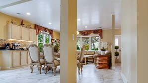 A spacious kitchen with marble flooring, a dining area with ornate chairs, and a view of the outdoors.