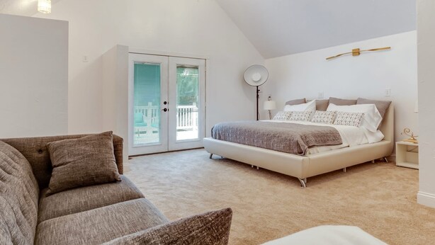 A bedroom with a bed, a sofa, a floor lamp, and a chandelier.