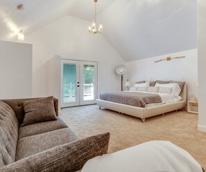 Ein Schlafzimmer mit einem Bett, einem Schlafsofa, einer Stehlampe und einem Kronleuchter.