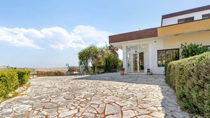 A modern house with a stone patio leading to a glass door entrance.