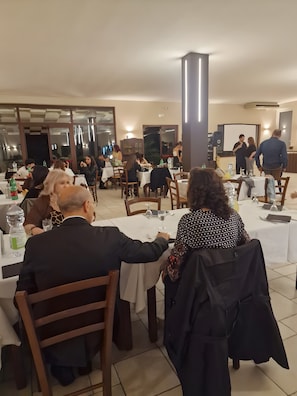 Un restaurant amb diverses taules, cadires i un ample piló.