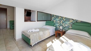 A hotel room with two beds, a television, and a patterned wall.