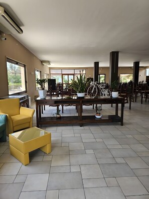 A spacious lobby with a large table, chairs, and potted plants.