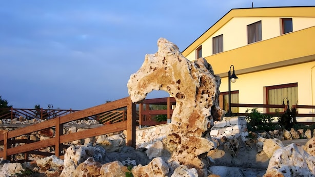 A stone structure with a wooden railing, a yellow building, and a clear sky.