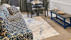 Un salon moderne avec un canapé, une table à manger, un lustre et un téléviseur fixé au mur.