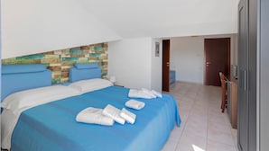 Een hotelkamer met een bed, een houten accentmuur, een deur en uitzicht op een andere kamer.