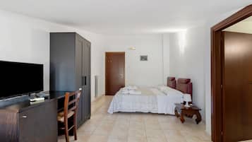 A hotel room with a bed, a desk with a TV, a wardrobe, and a bathroom.