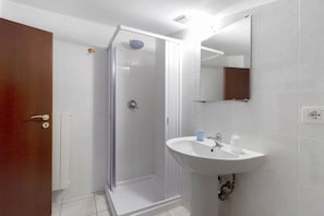 Baño con ducha, lavamanos y espejo.