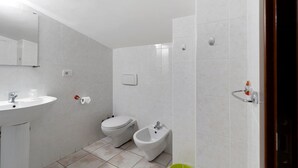 A modern bathroom with a sink, toilet, bidet, and a mirror. - Villa Ristòries Room 7 with Terrace, Wi-Fi, and Air Conditioning (Matera)