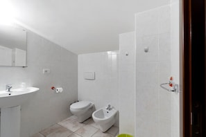 Ein modernes Badezimmer mit Waschbecken, Toilette, Bidet und Spiegel.