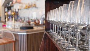 Een bar met een rij lege wijnglazen op een plank.