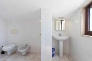 A bathroom with a toilet, bidet, and sink.