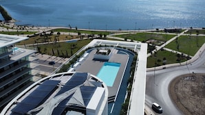 Un bâtiment moderne doté d’une piscine sur le toit, d’une route sinueuse et offrant une vue sur la mer.