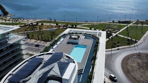 Un immeuble de grande hauteur doté d’une piscine sur le toit, d’une route sinueuse et offrant une vue sur la mer.