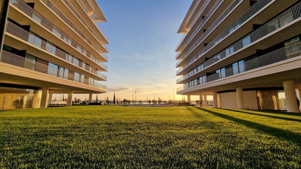 Un bâtiment moderne doté de nombreux balcons et d’une cour verdoyante.