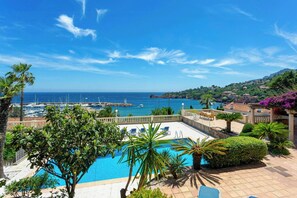 A pool with lounge chairs, a view of the sea, and a hillside with buildings. - Villa above La Figueirette harbour (Théoule-sur-Mer)