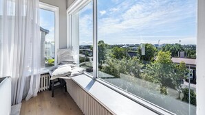 Ein Balkon mit Blick auf eine Stadtlandschaft, ein Heizkörper und ein Stuhl mit Kissen.