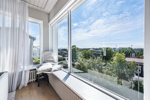 Ein Balkon mit Blick auf eine Stadtlandschaft, ein Heizkörper und ein Stuhl mit Kissen.